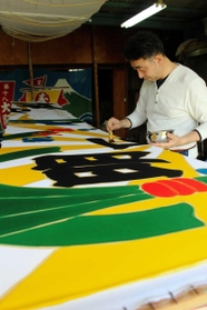 はけを使い、手作業の染色で大漁旗を仕上げる黒川さん＝明石市日富美町