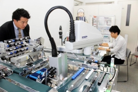 工場の品質管理システムを分かりやすく披露するミニチュアをチェックする従業員＝明石市魚住町