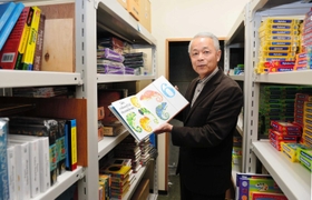 東京都新宿区の本部の倉庫で輸入絵本を開く工藤恭孝社長。大日本印刷グループに入った当時、洋書も取り扱う丸善書店の再建が課題だった（撮影・村中拓久）