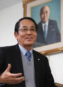 業界最大手・日本ジャバラ工業の２代目社長、田中信吾さん。後ろの肖像画は創業者の父貞雄さん＝神戸市兵庫区水木通９（撮影・小林良多）
