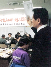 震災後に初めて開かれた兵庫県中小企業家同友会の例会で、新聞記事を手に関係者の近況を報告する田中さん（１９９５年２月２７日撮影、兵庫県中小企業家同友会提供）