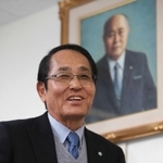 業界最大手・日本ジャバラ工業の２代目社長、田中信吾さん。後ろの肖像画は創業者の父貞雄さん＝神戸市兵庫区水木通９（撮影・小林良多）