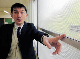 教室の暖房費を減らすために窓ガラスに貼り付けた断熱材を説明する壷井さん＝神戸市須磨区友が丘９、北須磨高校