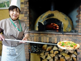 地元の広葉樹の薪で地域食材のピザを焼く大谷和子さん＝豊岡市日高町国分寺、ガンピー穀物倉庫