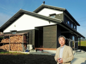省エネを徹底させ、薪ストーブを備えた住宅の魅力について語る熊田得男さん＝豊岡市内