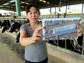 牛舎の屋根に付けた太陽光パネルを上空から写した写真を説明する渕上由美子さん＝神戸市西区神出町