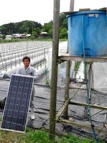 １枚の太陽光発電パネルの電気でピーマン畑に水をやる装置を使っている小西康之さん＝豊岡市但東町