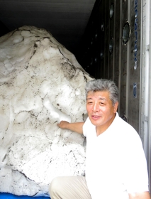 雪室の雪と今井悟さん。右上に並ぶ通気用の管でつながった隣のコンテナでは１～２度の低温で野菜などが冷蔵されている＝豊岡市日高町