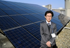 宝塚市役所屋上に並ぶ約２５０枚の太陽光発電パネルの前に立つ古南恵司さん＝同市東洋町