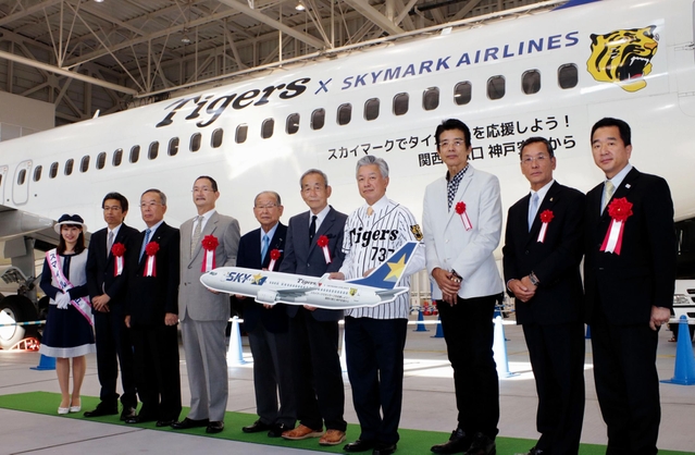 お披露目された特別機「タイガースジェット」の前に並ぶ参加者たち＝神戸市中央区、神戸空港