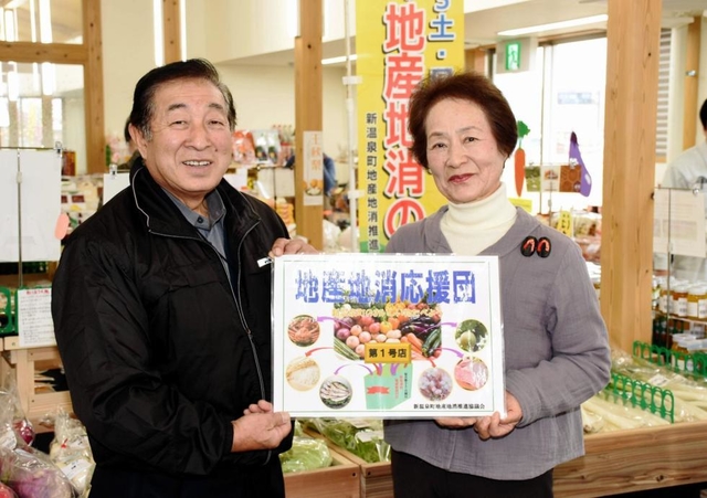 「地産地消応援団」のステッカーを手渡す松元けい子会長（右）と中村寿弘社長＝道の駅「山陰海岸ジオパーク浜坂の郷」