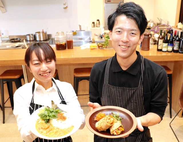 自慢の料理を手にする鷲田晃大さん（右）とホール担当の坂下未花さん＝洲本市本町４