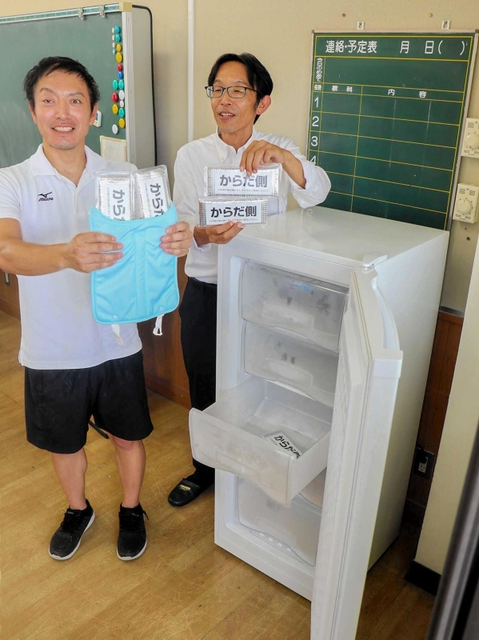 下校時の熱中症対策のために導入した冷凍庫をアピールする市教育委員会職員ら＝揖保小学校
