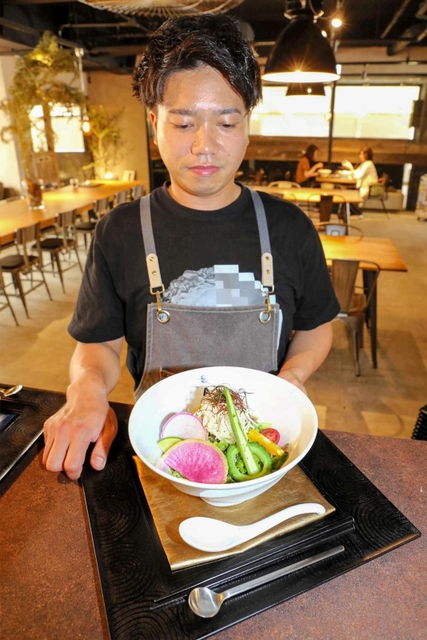 リゾートホテル風の店内で人気メニューのまぜそばを持つ店主の矢野英太郎さん＝姫路市城北新町