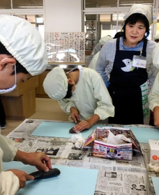 アジをさばく子どもたちを見守る福永美枝子さん＝宍粟市山崎町鹿沢、山崎小学校