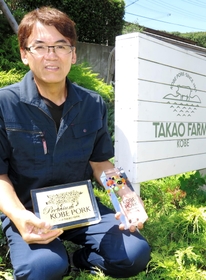神戸ポークプレミアム（左）と神戸ポークのシンボルマークを手にとって説明する高尾茂樹さん＝神戸市西区櫨谷町、高尾牧場