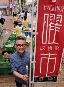 水曜市を始めた当初から使う赤いのぼりを手にする徳山隆秀さん＝神戸市中央区元町通１、元町一番街