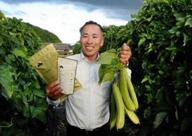 畑で採ったばかりのなた豆、なた豆茶を手にする小山伸洋さん＝丹波市春日町黒井
