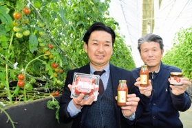濃厚な味わいの中玉トマト「夢茜」やジュース、ジャムを手にする西田朋広さん（左）と久保正彦さん＝兵庫県佐用町中三河、佐用まなび舎農園
