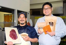 兵庫県内で捕らえられたシカを使ったペットフードとスマホカバーを持つ後藤高広さん（右）と、製造担当の坂本竜也さん＝兵庫県多可町加美区豊部