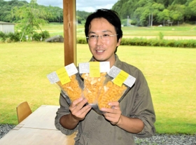 原料のコメを育てる田を一望する店内で生パスタを手にする小川陽平さん＝姫路市山田町、「パスタソリーゾ」