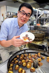 淡路島産の鳴門オレンジなどを使った商品を手にする長手康祐さん。手前は菓子に加工中の蒸したイチジク＝洲本市本町１