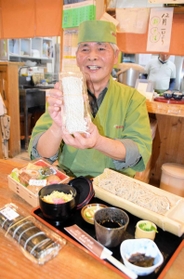 人気のざるそばや巻きずしを前に、打ちたての生そばを手にする藤井力雄さん＝小野市下来住町、そば処「ぷらっと　きすみの」
