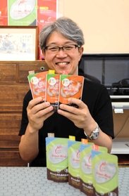 丹波地域産の有機米で作った「赤ちゃんのためのお粥（かゆ）」を手にする高寺寿一社長＝三田市武庫が丘３、グリーンマインド