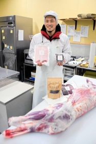 処理したシカを前に商品の肉やソーセージを手にする安倍育登さん＝豊岡市出石町奥山、安倍商会