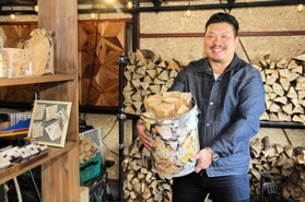 しっかり乾燥させた自慢の薪を入れたオリジナル缶を抱える西村嶺さん＝神戸市長田区苅藻通２