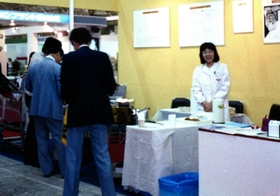 東京・晴海で開かれた見本市の出展ブースに立つ鯛かおるさん（右）＝１９８８年５月撮影（アトラステクノサービス提供）