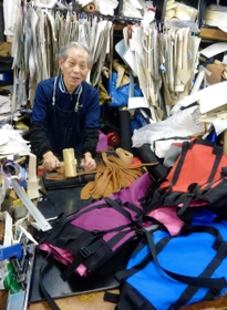 木づちで登山用ザックの肩掛けひもに穴をあける星加弘之さん。後継者はおらず、事業承継の候補者探しを進める＝神戸市長田区日吉町３、神戸ザック