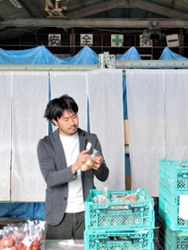 造船所のドック跡を活用した選果場で「八百ちゃんトマト」を手にする八百伸弥さん＝姫路市網干区大江島