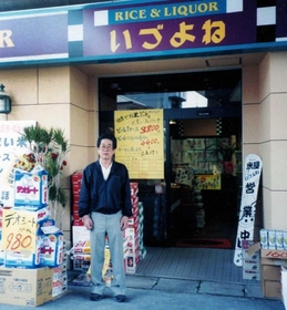 １９９６年４月下旬に開業した新店の前に立つ父・川崎武さん（いづよね提供）