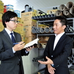 倉庫にある約3千種類の資材について解説する松田幸治社長（右）