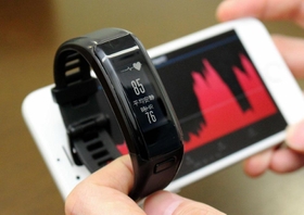心拍数を測ることができる活動量計。スマートフォン（奥）と連動させると、数値の推移も確認できる＝明石市二見町南二見