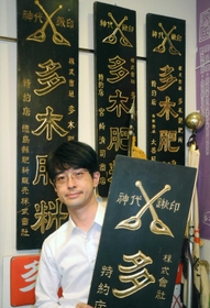 資料展示室で看板を持つ多木勝彦・取締役上席常務執行役員。神代鍬の印に「創業者の精神が感じられる」＝加古川市別府町緑町
