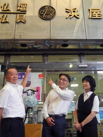 店の上部に掲げられた社章のロゴマークについて話す濱田明彦社長（中央）、花尾文彦取締役（左）ら＝神戸市中央区元町通４、浜屋神戸本店