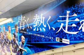 サッカー日本代表を応援するＴＯＹＯＴＩＲＥがＪＲ渋谷駅構内に掲示している広告（同社提供）