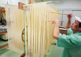 引き延ばした麺と麺が付かないように箸でさばく作業＝福崎町西田原、もちむぎのやかた