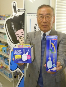 コトブキ浣腸を手にする西啓次郎会長。後ろは同社のキャラクター「ひとおしくん」＝淡路市尾崎