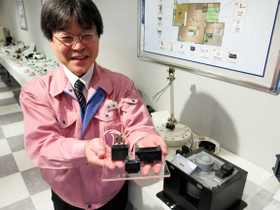 「空気清浄機の送風ファンなどにも使われています」と、コンデンサーを手にする森脇さん＝西宮市大社町、指月電機製作所