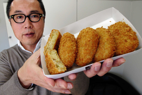 コロッケを持つ水野社長。「営業はしないけど、新規出店の引き合いは多いんです」＝神戸市東灘区深江浜町