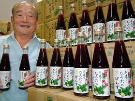 自慢のぽん酢を手に笑顔を見せる廣田豊会長＝尼崎市立花町４、手造りひろた食品本社
