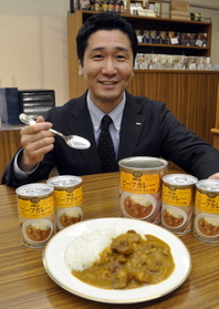 「タヒチカレー」を手にする水垣佳彦経営企画室長。「社内アンケートでも人気ナンバーワンを誇ります」＝神戸市東灘区深江浜町