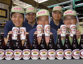 キリンラガーを手にする神戸工場のパッケージング担当者ら＝神戸市北区赤松台２