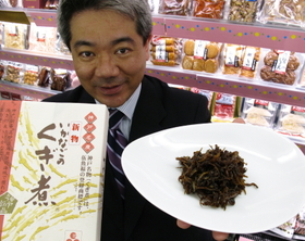 イカナゴのくぎ煮を持つ山中勧社長。「強火で硬めに炊くのがうちの特徴」＝神戸市長田区野田町８、伍魚福