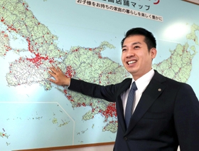 店舗を示す赤い印で染まる日本地図を指し示し、さらなる成長を誓う西松屋チェーンの大村浩一社長＝姫路市飾東町庄（撮影・辰巳直之）