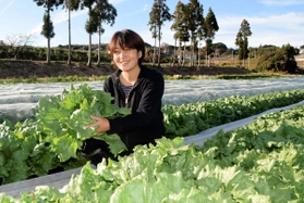 「寒さに当たり、甘みが一層増しておいしいですよ」とレタスを手にする西田美福さん＝淡路市小田