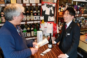 営業先の酒店主に新商品を紹介する白鶴酒造の吉岡千慶さん（右）＝神戸市東灘区御影本町２、三好商店（撮影・秋山亮太）